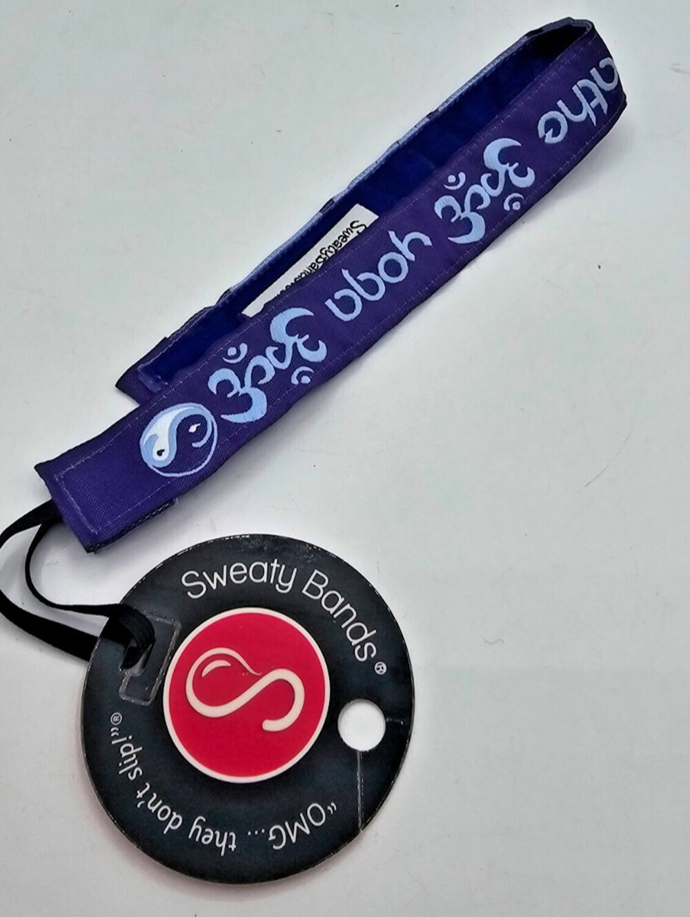 purple Sweaty Bands non-slip headband featuring white Om symbols and yin-yang